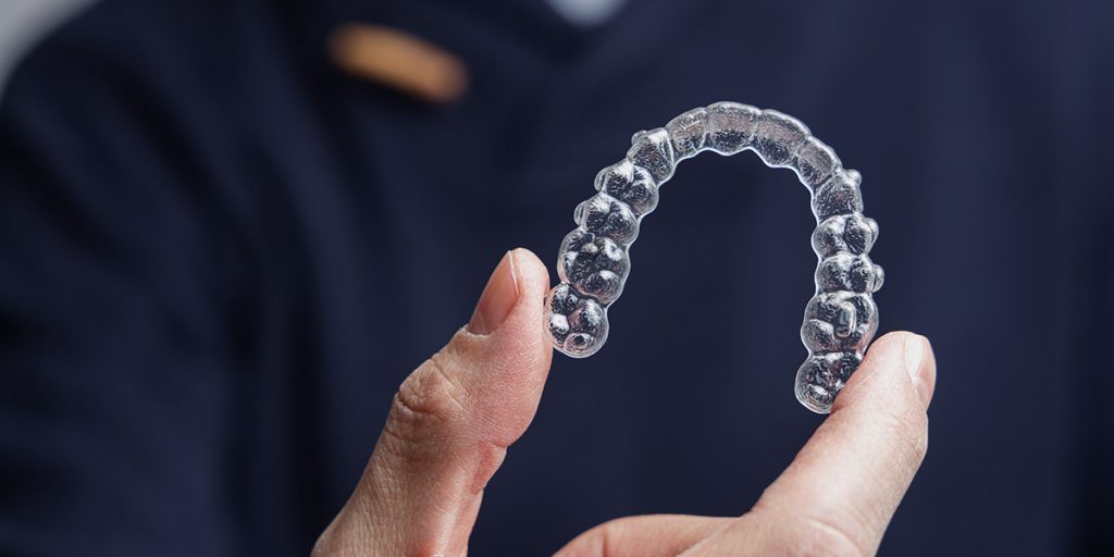 Dentist holding up invisalign clear aligners for invisalign bite correction