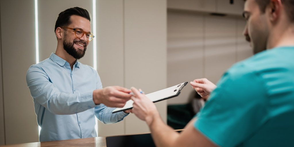 man smiling in dental reception making an appointment for severe toothache emergency
